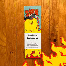 Load image into Gallery viewer, The set of bookmarks wrapped with a bellyband entitled “Boudicca bookmarks”, pictured here with yellow and red fire made of paper.