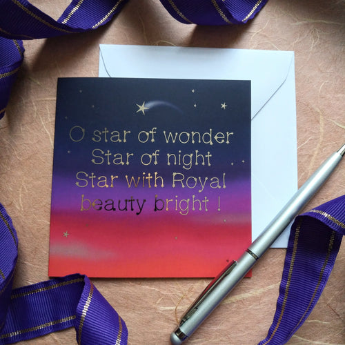 Photo of a card showing the night sky and sunset in colours from deep red to purple and stars against dark blue. A shooting star is among all the others. The text, in gold type, reads “O star of wonder Star of night Star with Royal beauty bright!”. Next to the card is a white envelope, silver pen, and a curling purple ribbon.